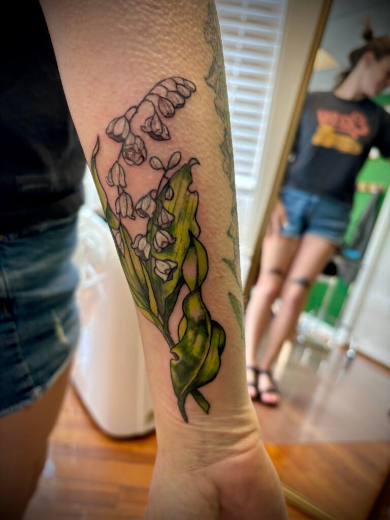 Lilly of the Valley illustrative color tattoo on forearm